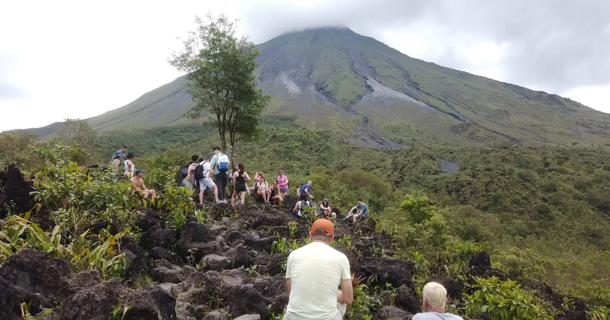 Hikers on the lava-field trail at the base of Arenal Volcano on a volcano hike and thermal river tour from La Fortuna, Costa Rica
